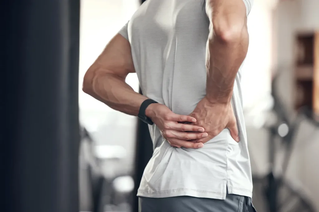 Man holding his lower back in pain at the gym